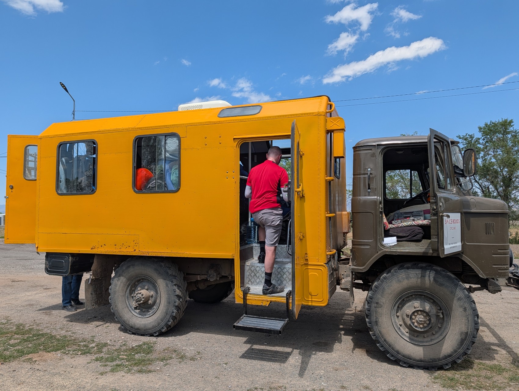 Yellow support truck with riders climbing aboard